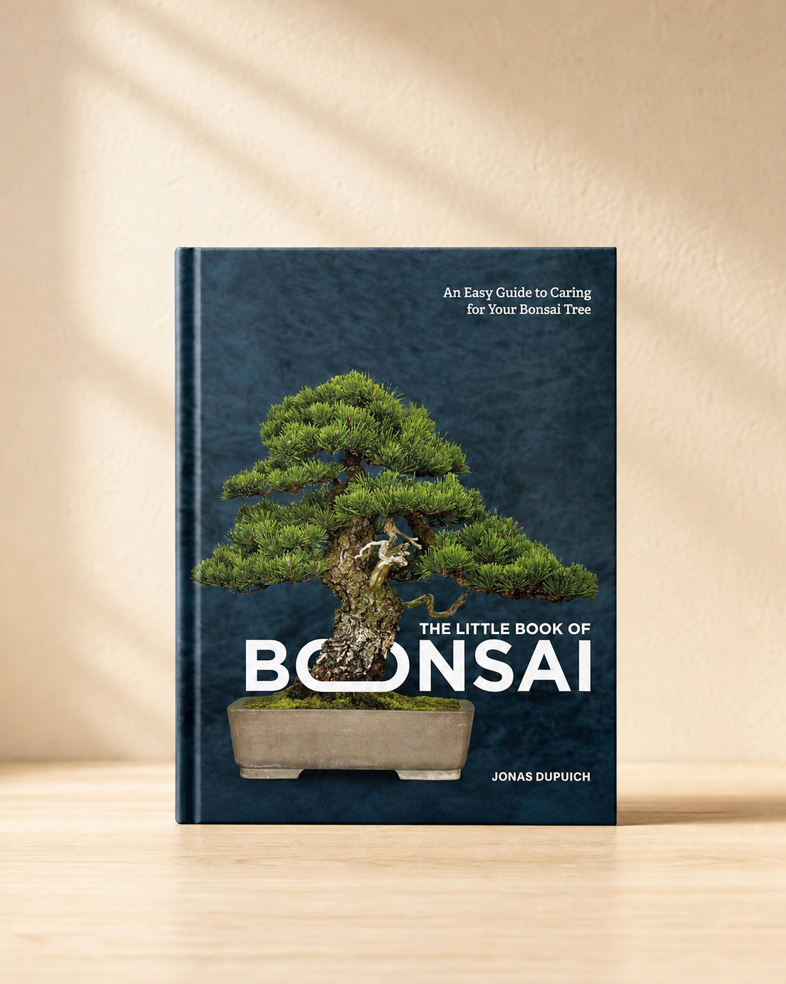 The Little Book of Bonsai hardcover standing on pale oak against a warm ivory backdrop